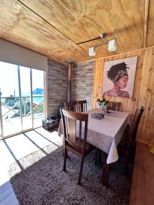 a dining room with a table with chairs and a painting at Cabañas Emma Maicolpue in Osorno