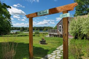 ein Holzschild in einem Hof mit einem Haus in der Unterkunft Cozy Pond Side Cottage in Bar Harbor! [The Nook] in Bar Harbor