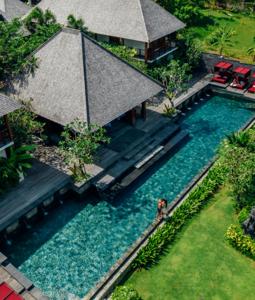 una vista aérea de una piscina con una persona parada en el agua en La Reserve 1785 Canggu Beach - Adults Only, en Canggu