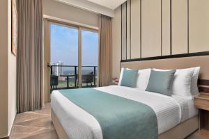 a bedroom with a large bed and a large window at Citadines Paras Square Gurugram in Gurgaon