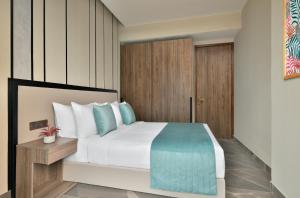 a bedroom with a large white bed with blue pillows at Citadines Paras Square Gurugram in Gurgaon