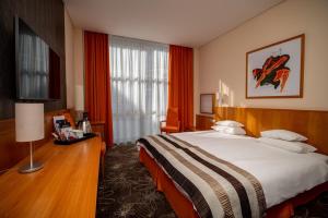 um quarto de hotel com uma cama grande e uma secretária em Hotel Lycium Debrecen em Debrecen