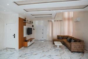 ein Wohnzimmer mit einem braunen Sofa und einem TV in der Unterkunft Elegant and Cosy Four Bedroom Home in Accra in Accra