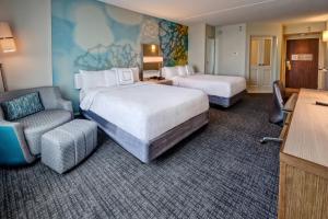 ein Hotelzimmer mit 2 Betten und einem Stuhl in der Unterkunft Courtyard by Marriott Dulles Airport Herndon in Herndon