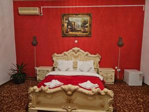 a bedroom with a gold bed with a red wall at Pensiunea Crown Royal in Alba Iulia