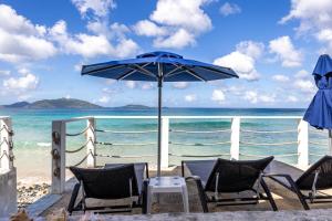 una mesa y sillas en una playa con sombrilla en Sebastian's on the beach hotel, en Road Town