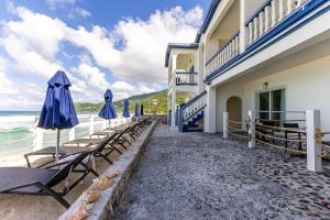 una fila de sillas y sombrillas junto a un edificio en Sebastian's on the beach hotel, en Road Town