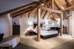 - une chambre principale avec un grand lit et des poutres apparentes dans l'établissement Hotel Acadia - Adults Mountain Home, à Selva di Val Gardena