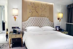 - une chambre avec un grand lit blanc et une grande tête de lit dans l'établissement Estandon Hotel Guangzhou, à Canton