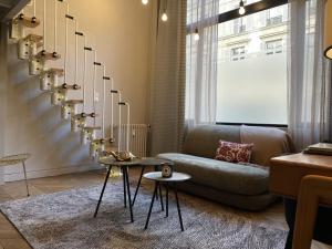 een woonkamer met een bank en een kroonluchter bij Loft Royal des Promenades in Reims