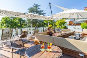 une femme assise sur un canapé sur un patio dans l'établissement Hotel Villa Elben Lörrach bei Basel, à Lörrach