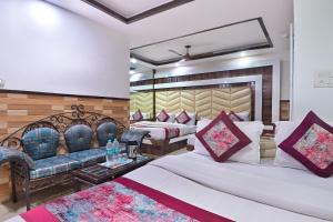 um quarto de hotel com duas camas e um sofá em Hotel Glow Inn Paharganj-3 Mins Walk From New Delhi Railway Station em Nova Deli