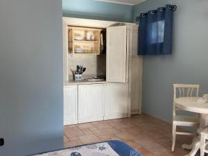 una cucina con armadi bianchi e tenda blu di Hotel Villa Del Parco a La Maddalena