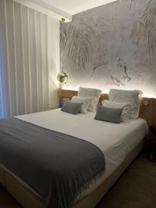 una camera da letto con un grande letto con lenzuola e cuscini bianchi di Charm-In Center a Vila Nova de Milfontes