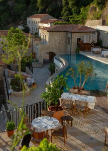 a pool with tables and chairs next to a resort at Zoe Hora in Dhërmi