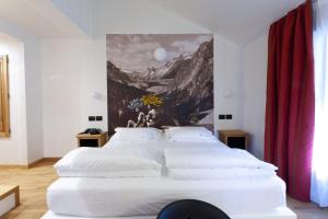 1 dormitorio con 1 cama blanca grande y una pintura en la pared en Hotel Berthod, en Courmayeur