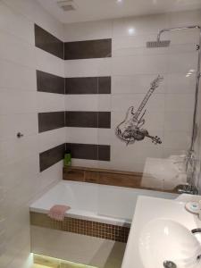 ein Badezimmer mit einer Badewanne mit einer Gitarre an der Wand in der Unterkunft Roses Apartment in Frýdek-Místek