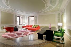 a living room with a red couch and green chairs at Palazzo Dei Fiori by Room Mate in Venice