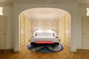 a bedroom with a white bed and a red bench at Palazzo Dei Fiori by Room Mate in Venice