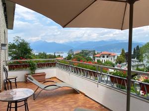 einen Balkon mit einem Tisch, Stühlen und einem Sonnenschirm in der Unterkunft Hotel La Fontana in Stresa