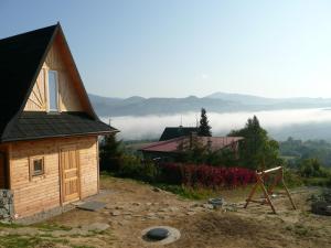 une petite maison sur une colline avec des nuages en arrière-plan dans l'établissement Domki na Polach Piwniczna-Zdrój, à Piwniczna-Zdrój