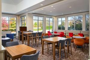 ein Restaurant mit Tischen, Stühlen und Fenstern in der Unterkunft Hilton Garden Inn Schaumburg in Schaumburg