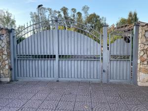 un cancello aperto con una recinzione bianca e un muro di pietra di CLARABELLA a Ponte Galeria