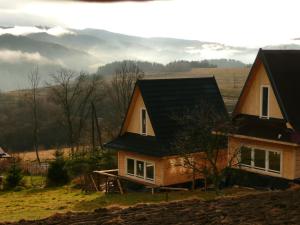 une maison avec un toit noir sur une colline dans l'établissement Domki na Polach Piwniczna-Zdrój, à Piwniczna-Zdrój