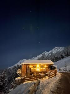 uma casa coberta de luzes na neve à noite em Das Grünholz Aparthotel em Mühlbach am Hochkönig