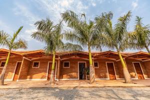 uma casa com três palmeiras em frente em Rancho da Cachaça Pousada em Holambra