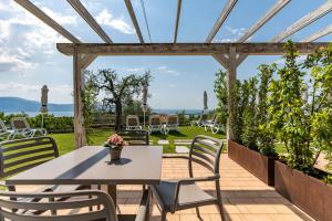 une table et des chaises sur une terrasse avec pergola dans l'établissement La Chioma di Berenice Garda Residence, à Toscolano Maderno