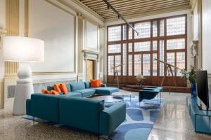 a living room with blue couches and orange pillows at Palazzo Dei Fiori by Room Mate in Venice