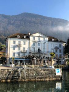 un grand bâtiment blanc à côté d'une étendue d'eau dans l'établissement Seehof Hotel Du Lac, à Weggis