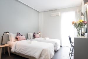 Duas camas num quarto branco com almofadas cor-de-rosa em Athens Studios em Atenas