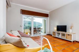 ein Wohnzimmer mit einem Sofa und einem TV in der Unterkunft Casa do Mar - Sea view - Wifi - Barbecue in Sesimbra