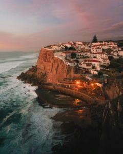 un pueblo en un acantilado cerca del océano por la noche en Azenhas do Mar Roadside House, en Colares