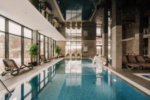 Hotel Saltic Resort & Spa Grzybowo في كولوبرزيغ: مسبح في مبنى فيه كراسي ومسبح