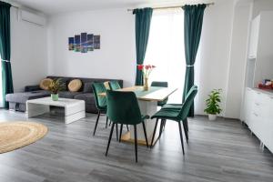 ein Wohnzimmer mit einem Tisch und grünen Stühlen in der Unterkunft Apartament Radiana in Baile Felix