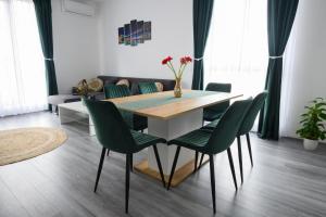 ein Esszimmer mit einem Tisch und grünen Stühlen in der Unterkunft Apartament Radiana in Baile Felix