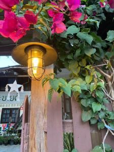 une lumière sur une clôture en bois avec des fleurs roses dans l'établissement Khonesavane Hostel, à Luang Prabang