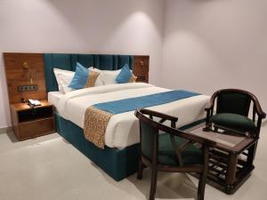 a bedroom with a bed and a chair at Emerald Suites in Greater Noida