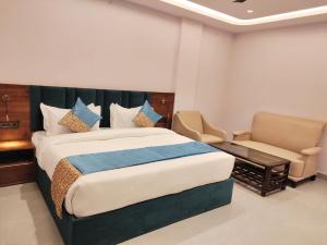 a bedroom with a large bed and two chairs at Emerald Suites in Greater Noida