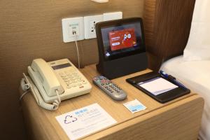 un teléfono y una tablet en una mesa en una habitación de hotel en Holiday Inn Express Shanghai Jinsha, an IHG Hotel, en Shanghái