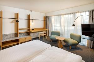 ein Hotelzimmer mit einem Bett, 2 Stühlen und einem Schreibtisch in der Unterkunft Palmiers by Fassbind in Lausanne