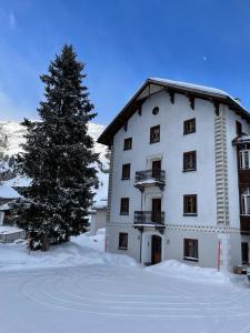 ein großes weißes Gebäude mit einem Baum im Schnee in der Unterkunft Roccabella in Bivio