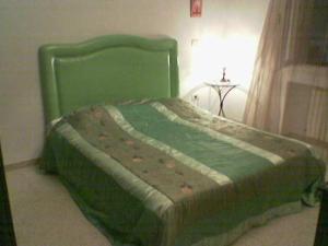 uma cama verde num quarto com uma mesa em My Second Home em Tunes