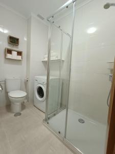 ein Badezimmer mit einer Dusche, einem WC und einer Waschmaschine in der Unterkunft Apartamento La Planchada in El Astillero