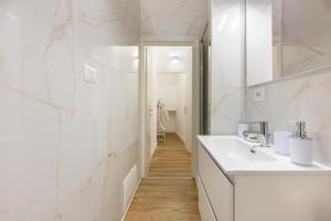 Baño blanco con lavabo y espejo en Fior Di Loto Rooms, en Cagliari