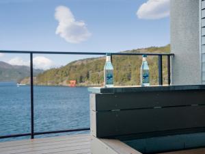 2 botellas sentadas en un balcón con vistas a un cuerpo de agua en Rakuten STAY FUJIMI TERRACE Hakone Ashinoko, en Hakone