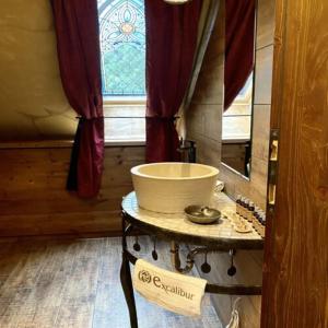 La salle de bains est pourvue d'une table, d'un lavabo et d'une fenêtre. dans l'établissement Excalibur miniHotel, à Eger